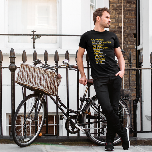 Man standing next to a bicycle with a basket, wearing a black t-shirt with text.