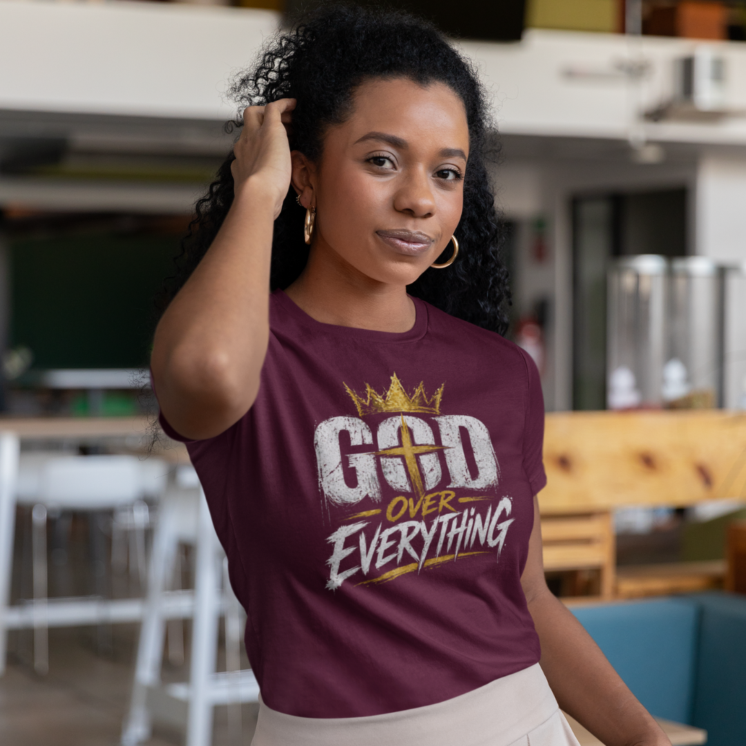 Woman wearing a maroon t-shirt with 'God Over Everything' text in a casual setting.