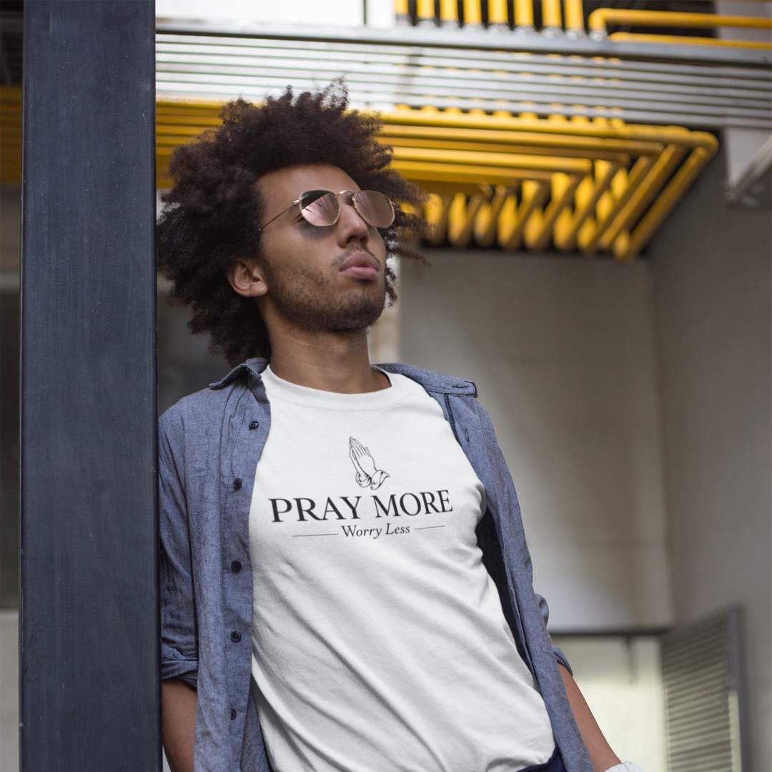 Man wearing a t-shirt with 'Pray More Worry Less' text in an urban setting