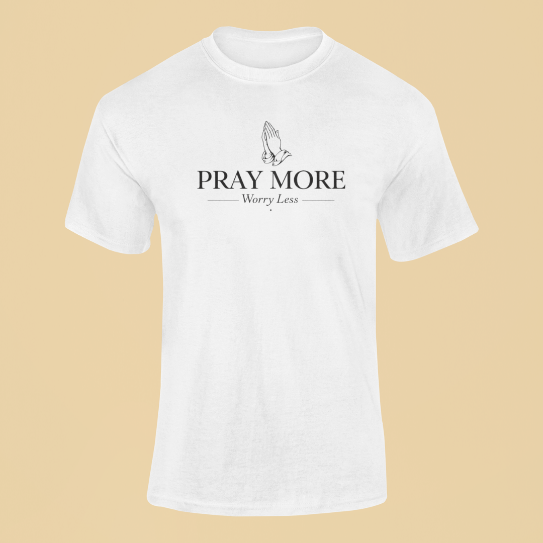 White t-shirt with 'PRAY MORE Worry Less' text and praying hands graphic on a beige background