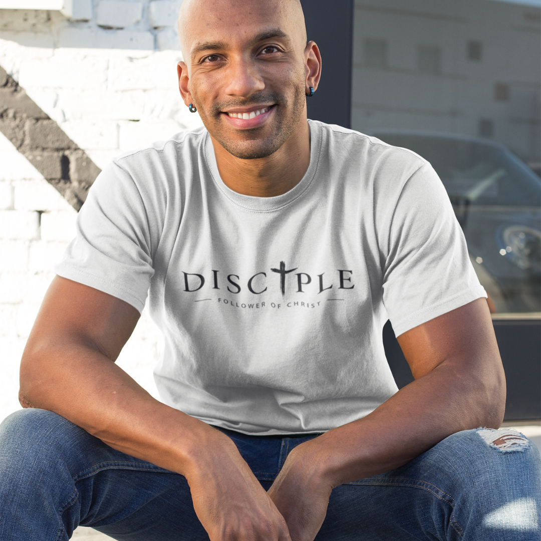 Man wearing a white t-shirt with 'DISCIPLE' printed on it, sitting outdoors.
