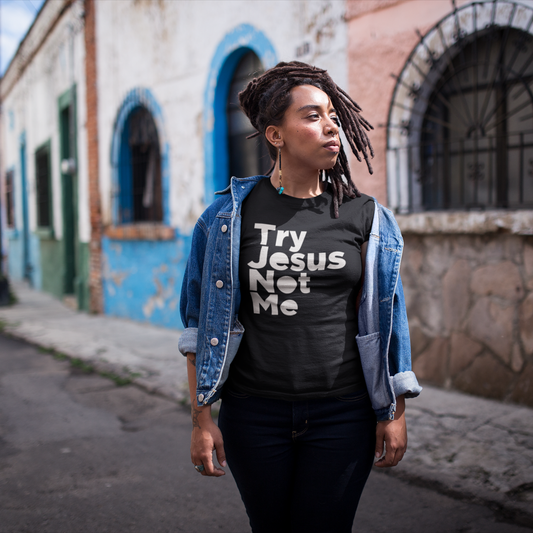 Person wearing a black t-shirt with 'Try Jesus Not Me' text, standing on a street.