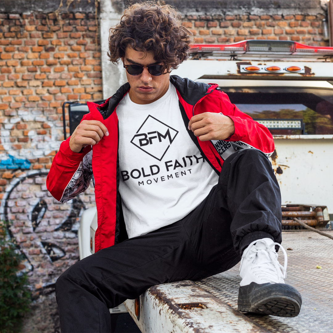 Person wearing a white t-shirt with 'Bold Faith Movement' logo and red jacket sitting on a vehicle.