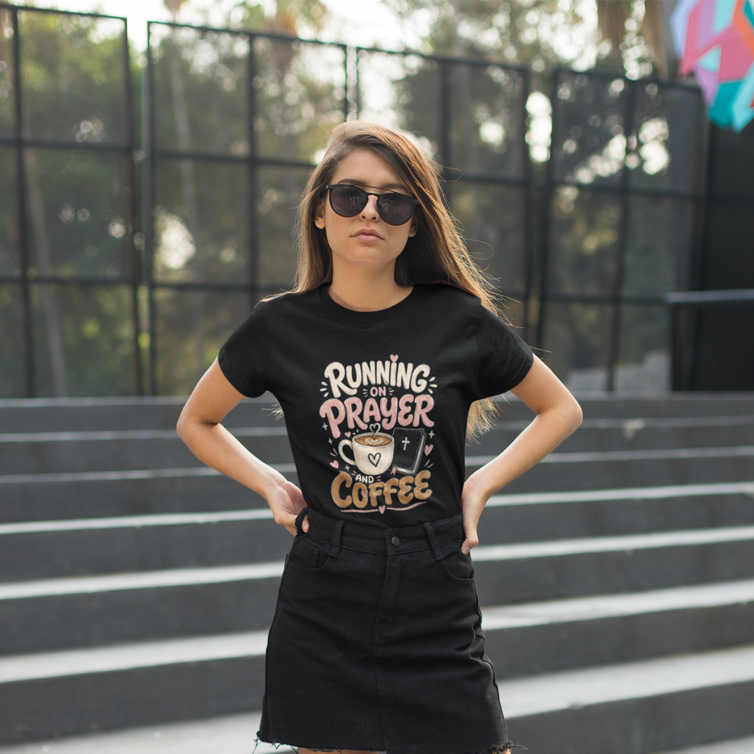 Woman wearing a black t-shirt with 'Running on Prayer and Coffee' text, standing outdoors.