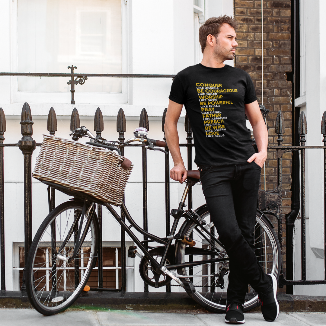 Man standing next to a bicycle with a basket, wearing a black t-shirt with text.