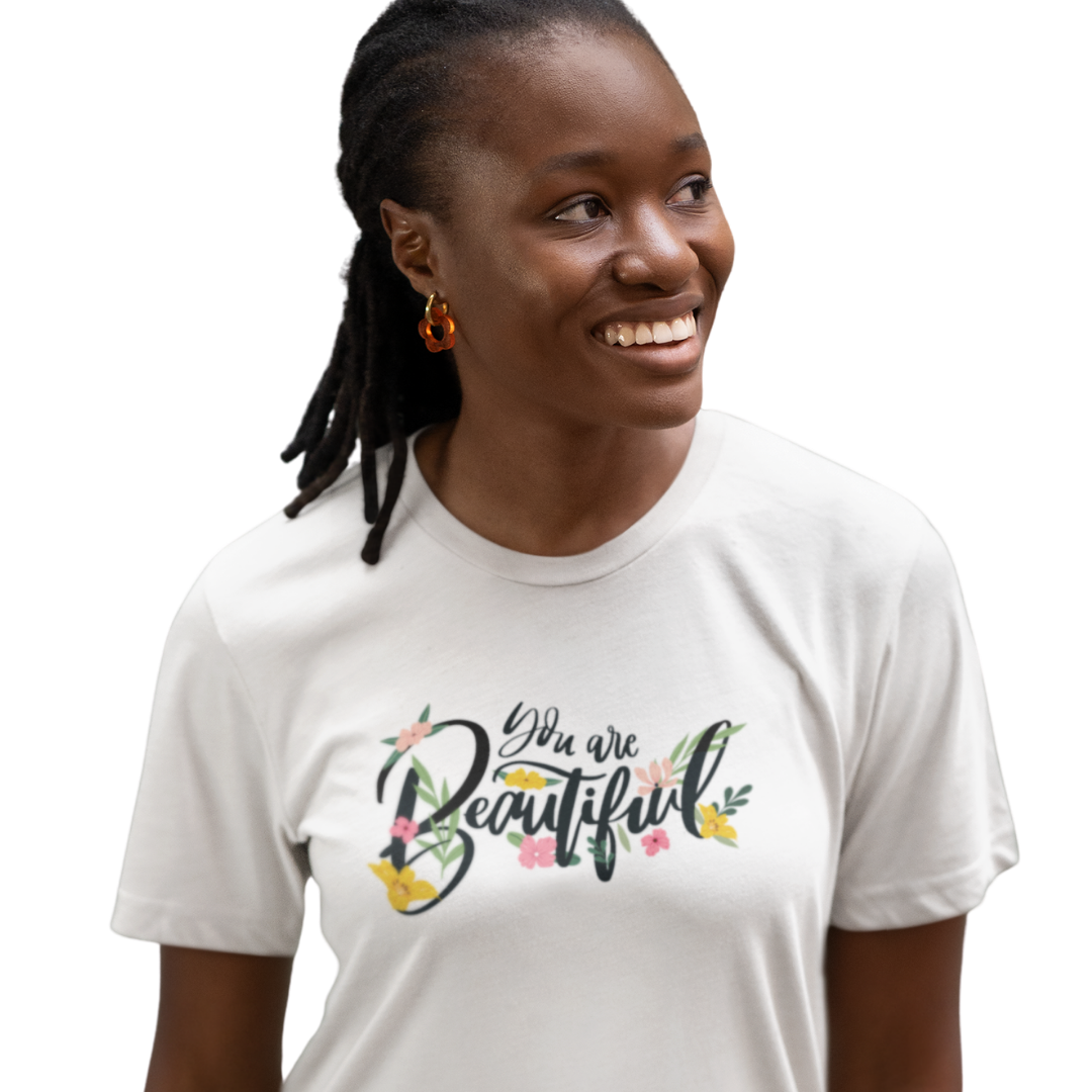 Woman wearing a white t-shirt with 'You are Beautiful' text and floral design on a plain background