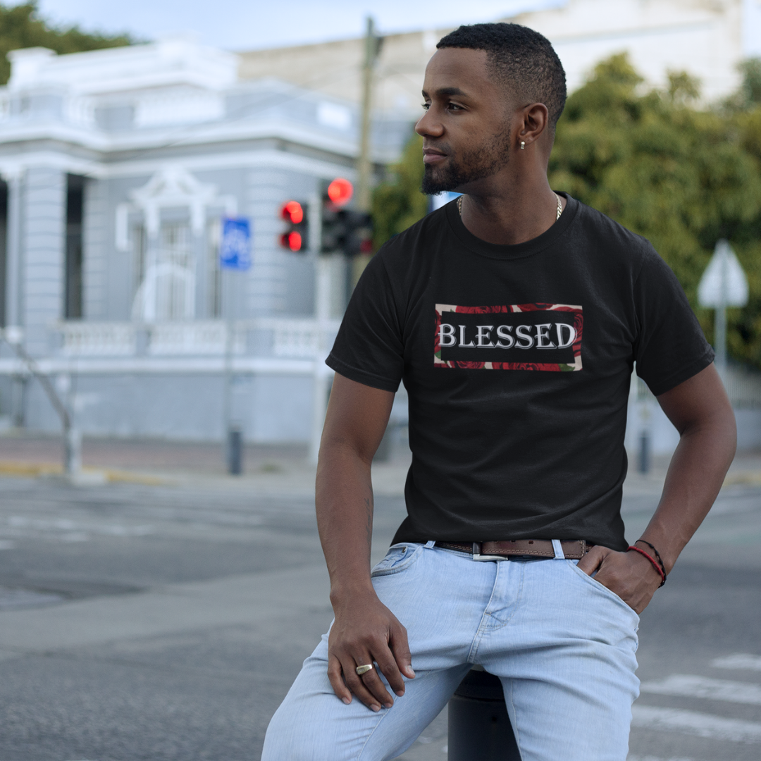 Man wearing a black t-shirt with 'BLESSED' printed on it, standing on a street.