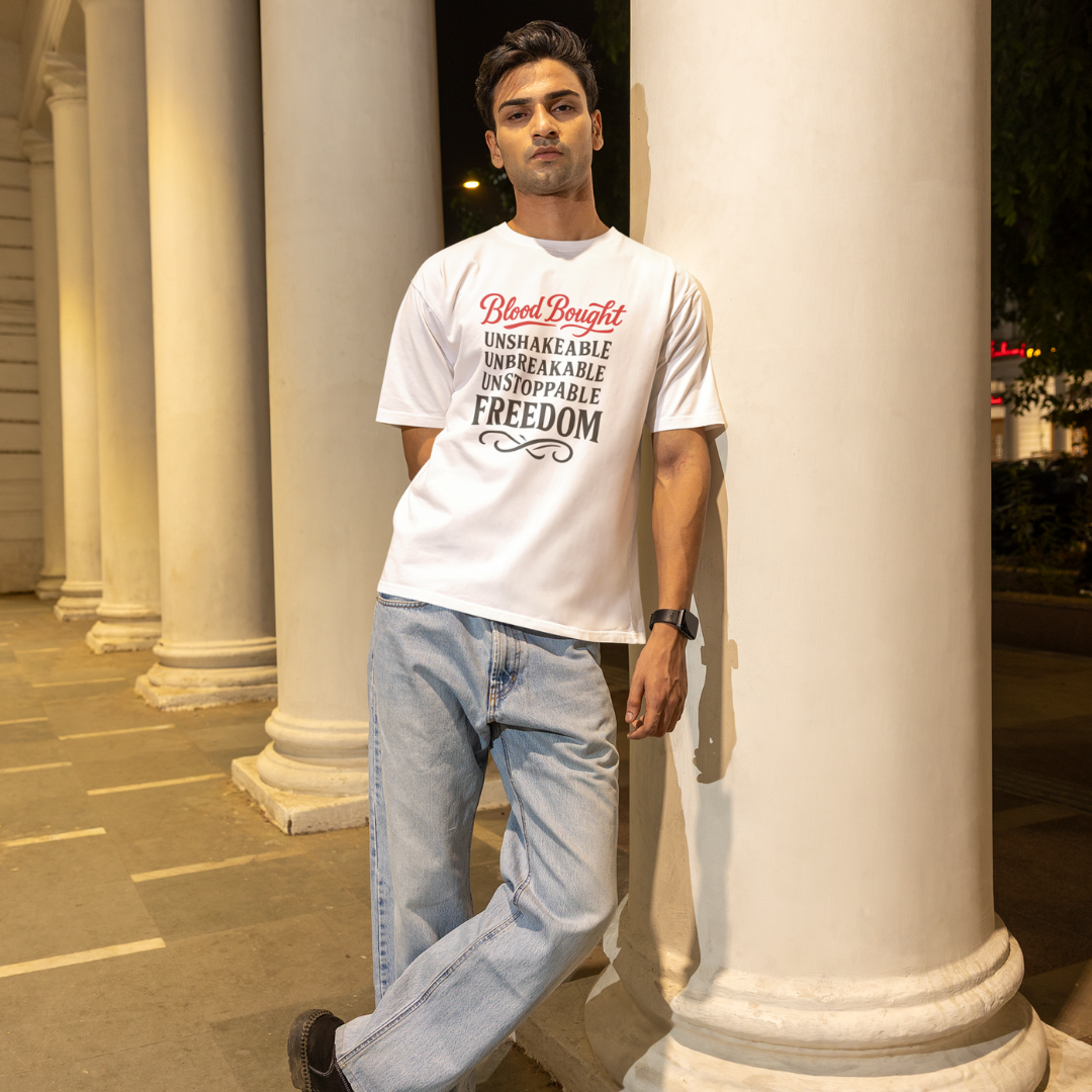 Man wearing a white t-shirt with text standing in front of classical columns.